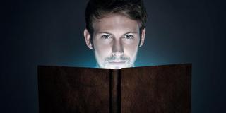 Der gekaufte Bestseller: Mann liest vor dunklem Hintergrund in einem Buch