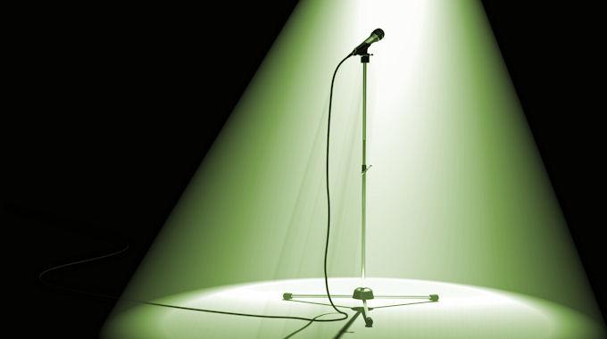 Mikrofonständer im grünen Spotlight einer Bühne; Autorencasting im TV, wasliestdu.de